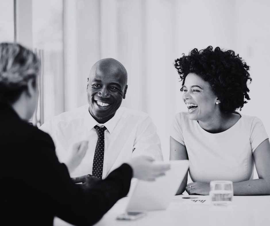 Professionals around a table laughing.